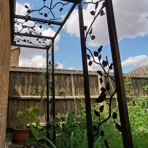 a metal trellis with a potted plant next to it
