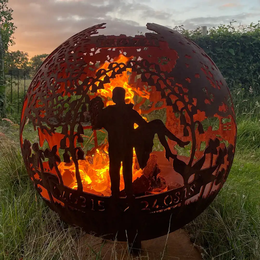 a metal sculpture of a man holding a child in front of a fire