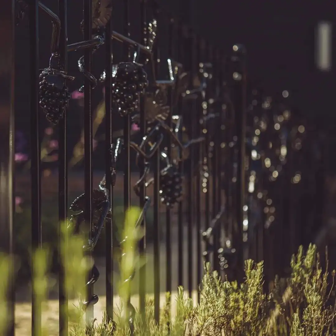 a close up of a metal fence with plants