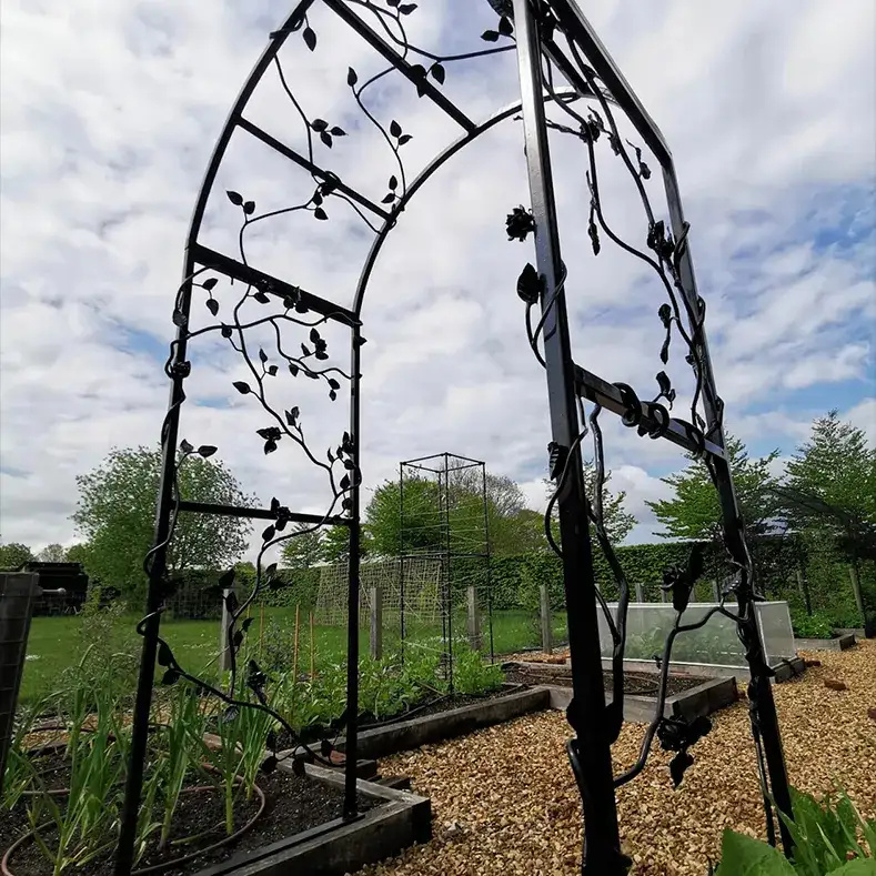 a large metal arch in a garden filled with lots of plants